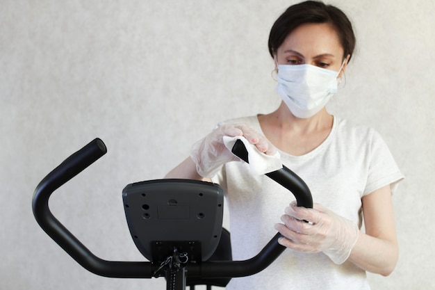 Die maskierte Frau reinigt den Simulator mit einem Desinfektionstuch, um die Ausbreitung des Virus zu verhindern. Stoppen Sie das Coronavirus.