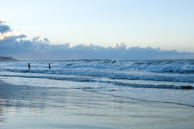 Die Menschen schwimmen im Morgengrauen im Meer. Schwimmen im stürmischen Meer ist gefährlich. Spaziergänge an der Küste in den frühen Morgenstunden.