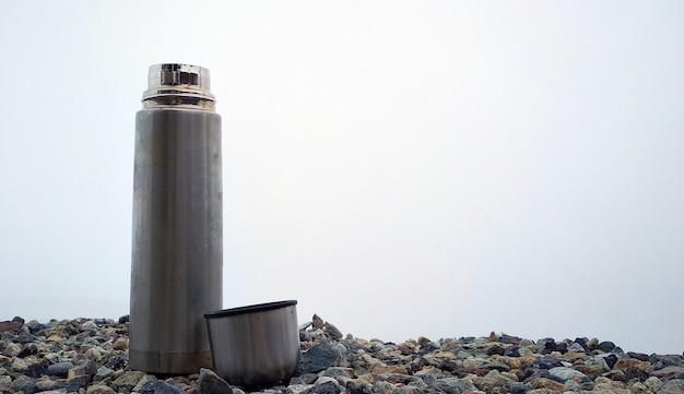 die Metallthermosflasche auf Bergsteinen