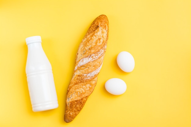 Die Mindestmenge an Produkten zum Frühstück. Brot, Eier und Milch auf gelbem Grund