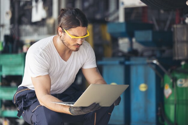 Die Mitarbeiter des Autoservices überprüfen die Boden- und Unterfahrschutzplatten unter dem angehobenen Auto