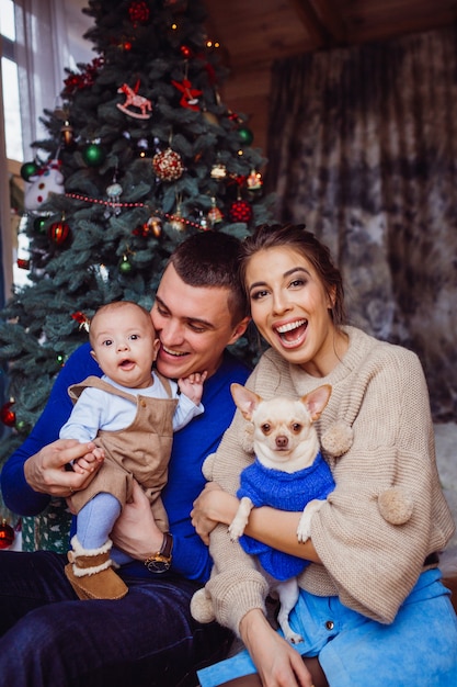 Die Mutter, der Vater, der Hund und das Baby, die nahe Weihnachtsbaum sitzen