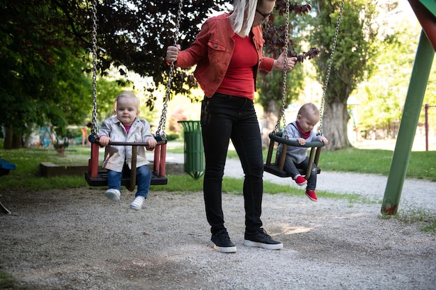 Die Mutter, die ihr Baby schiebt, hat Spaß auf der Schaukel