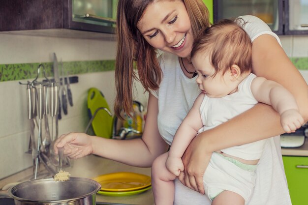 Die Mutter einer Frau mit einem Baby kocht das Essen in einem Topf auf dem Herd