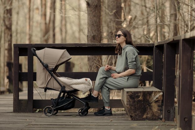 Foto die mutter entspannt sich auf der bank, während ihr kind im kinderwagen schläft