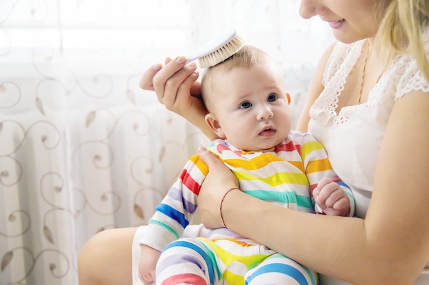 Die Mutter kämmt die Haare des kleinen Babys