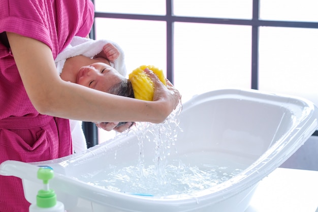 Die Mutter putzte das Baby auf dem weißen Tuch, während die Morgensonne schien.