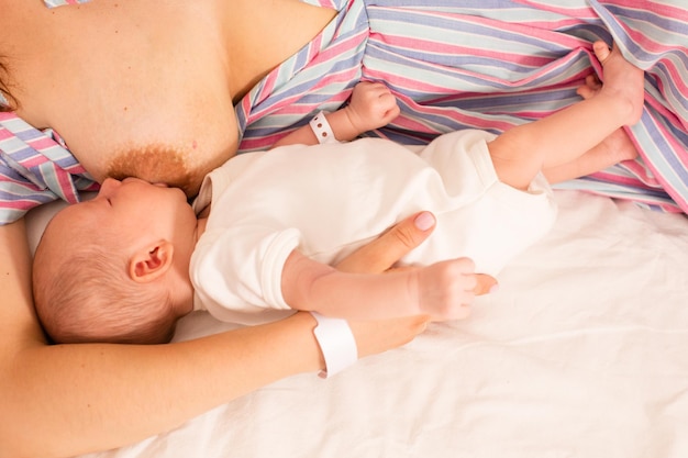 Die Mutter stillt ihr neugeborenes Baby auf dem Bett