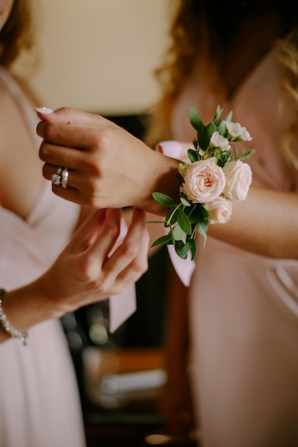 Die Nahaufnahme der Hände der Braut, die das Hochzeitsarmband an der Hand der Brautjungfer binden.