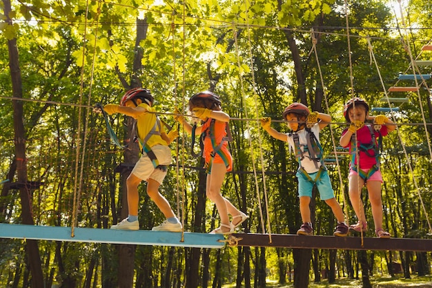 Die niedlichen Kleinen gehen nacheinander in den Seilpark. Die in Schutzkleidung gekleideten Kinder halten sich am Seil fest und treten auf die Reifen