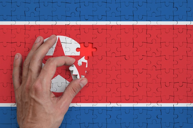 Die Nordkorea-Flagge ist auf einem Puzzle abgebildet, das mit der Hand des Mannes gefaltet wird