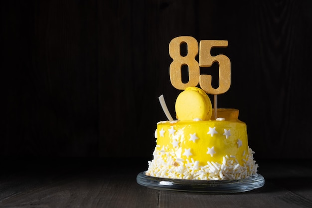 Die Nummer fünfundachtzig auf einem gelben Kuchen zum Jubiläum oder Geburtstag in einem dunklen Schlüssel