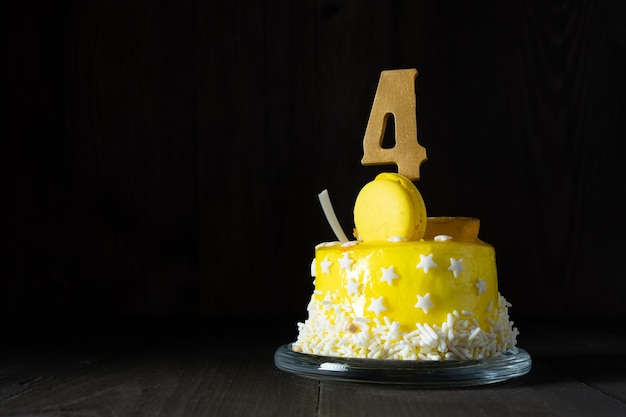 Die Nummer Vier auf einem gelben Kuchen zum Jubiläum oder Geburtstag in einem dunklen Schlüssel