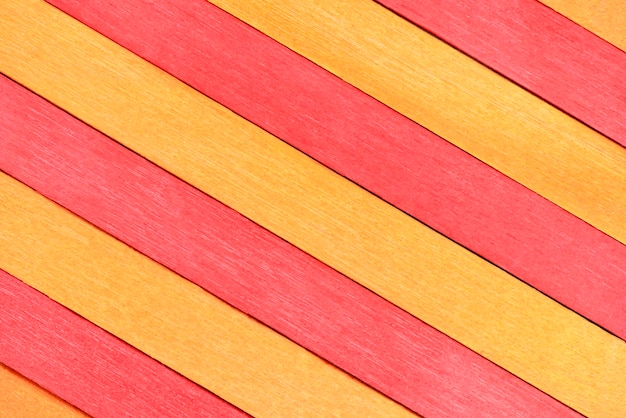 Die Oberfläche aus abwechselnd roten und orangefarbenen Holzbohlen, die diagonal angeordnet sind