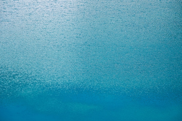 Die Oberfläche ist blaues Wasser mit Wellen vom leichten Wind und Reflexionen. Abstraktes Wasser perfekter Hintergrund.