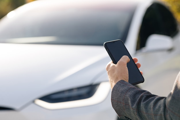 Die Person steuert ein selbstfahrendes Elektroauto unter Verwendung einer mobilen Anwendung