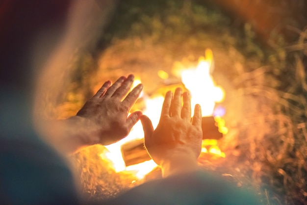 Foto die person wärmt sich die hände über dem lagerfeuer. abend nacht zeit