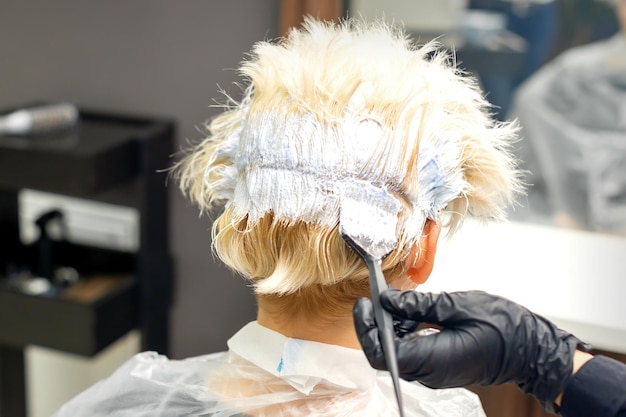 Die professionelle Friseurin färbt ihrer Kundin in einem Schönheitssalon die Haare.