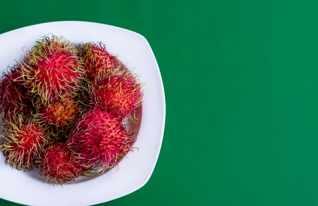 Die Rambutans sind in einer Platte auf Grünbuchhintergrund