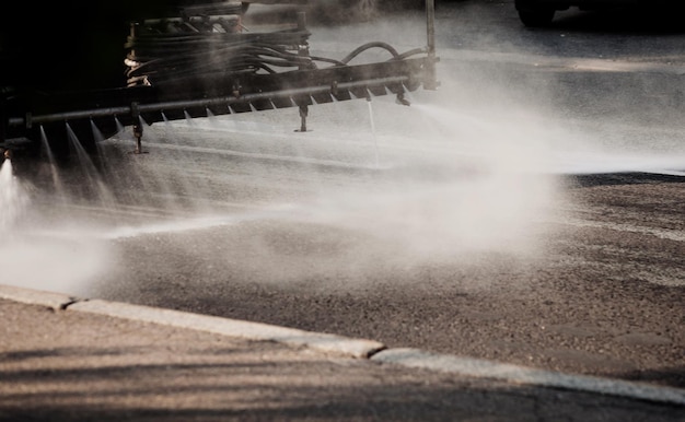 Foto die reinigung von flusher-kehrmaschinen wäscht die straßen der stadt mit wassersprühgruppen von kommunalen bewässerungsmaschinen, die asphalt waschen