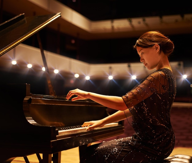 Die richtigen Töne treffen Einstellung einer jungen Frau, die während eines Musikkonzerts Klavier spielt