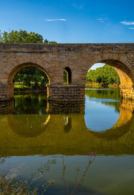 Die römische Brücke von Merida über den Fluss Guadiana mit ihrer symmetrischen Reflexion im Wasser