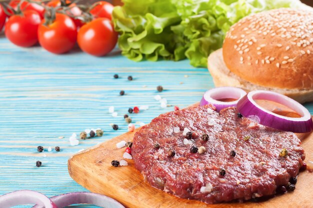 Die rohstoffe für den hausgemachten burger auf blauem holztisch.