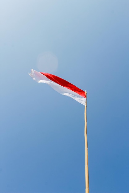 Die rot-weiße Flagge Bendera Indonesien flattert im Wind am blauen Himmel