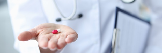 Die rotweiße Pille steht auf dem Konzept des Arzthandbuchs für Medikamente
