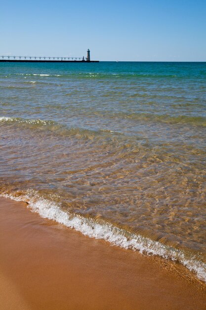 Foto die ruhige küste des michigansee mit goldenem sand und einem klassischen leuchtturm