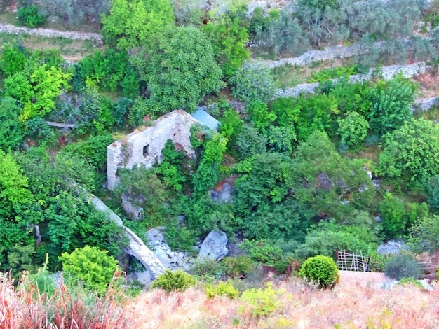 Die Ruinen einer alten Festung Alte dicke Steinmauern einer europäischen Festung, die mit Grün in den Bergen bewachsen sind Türen und Bögen in den Ruinen der Befestigungsanlagen