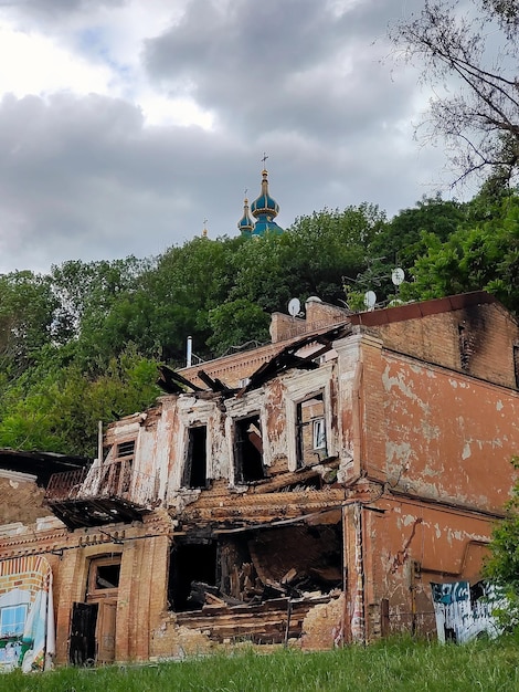 Die Ruinen eines alten Hauses im Vordergrund, dahinter ein Wald und die Kuppeln einer Kirche