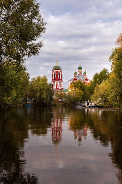 Die russische Kirche spiegelt sich im Teich wider, der von bunten Herbstbäumen umgeben ist PereslavlZalessky Russland