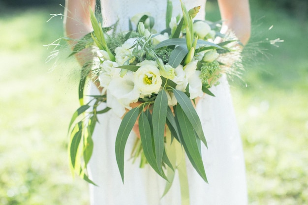 Die schöne Braut im Hochzeitskleid lächelte glücklich und hielt einen Blumenstrauß