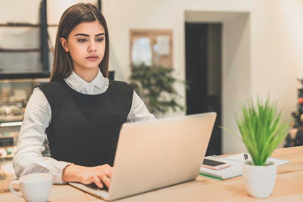 Die schöne Geschäftsfrau, die mit einem Laptop arbeitet