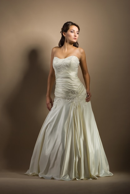 Die schöne junge Frau posiert in einem Hochzeitskleid