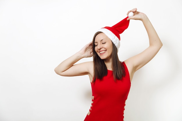 Die schöne kaukasische junge glückliche Frau mit gesunder Haut und charmantem Lächeln trägt rotes Kleid mit Weihnachtsmütze auf weißem Hintergrund. Santa Mädchen isoliert Porträt. Neujahrsferien 2018 Konzept