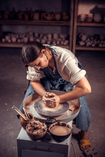 Die schöne Töpfermeisterin arbeitet mit Ton auf einem Töpferrad und am Tisch mit den Werkzeugen. Handwerk.