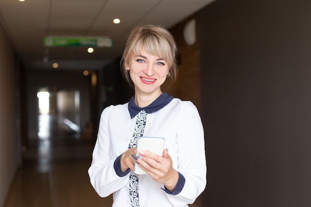 Die schöne und fröhliche Blondine mit Telefon