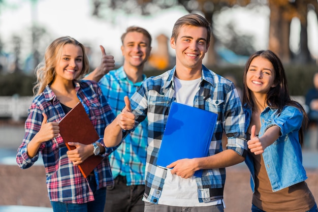 Foto die schüler gehen in den park und zeigen daumen hoch im park.