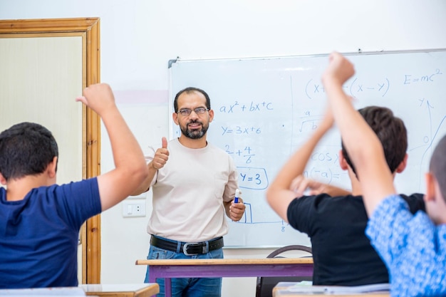 Die Schüler heben ihre Hände zur Teilnahme und beantworten die Frage des Lehrers