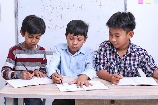 die schüler schreiben im klassenzimmer eine lektion über ein buch, üben und beenden die aufgabe gemeinsam