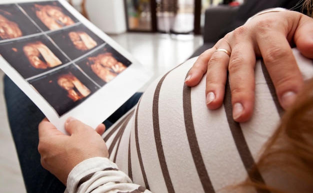 Foto die schwangere frau betrachtet das foto ihres kindes, das durch ultraschall gemacht wird