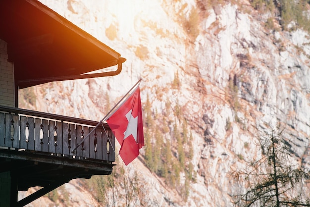 Die Schweizer Flagge mit einem weißen Kreuz auf rotem Hintergrund schwebt auf dem Haus und bietet eine landschaftliche Attraktion des Dorfes Grindelwald und der Berge.