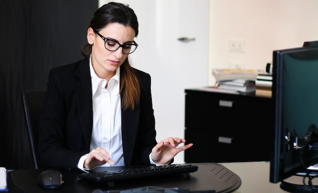 Die Sekretärin arbeitet in ihrem Büro mit einem Desktop-PC