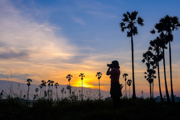 Die Silhouette der Touristen, die das Morgenlicht mit dem Tan Ton in der Provinz Pathum Thani aufgenommen haben