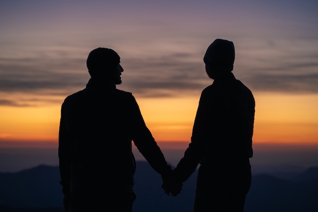 Die Silhouette des Paares auf dem Berg mit Sonnenaufgangshintergrund