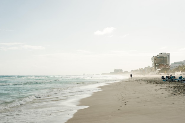 Die Silhouette einer Person an einem ansonsten menschenleeren Strand, der Wind bläst den Sand in Streifen über den Strand