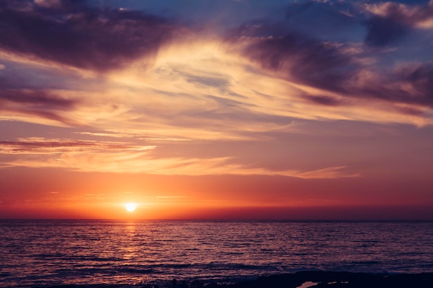 Die Sonne erscheint über dem Meer in einem rötlichen Himmel