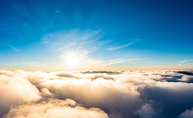 Die Sonne scheint bei Sonnenaufgang hell über weißen, flauschigen Wolken